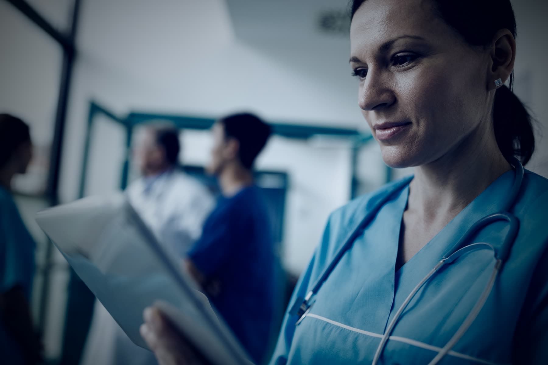 Profissional de saúde consultando um tablet em um corredor hospitalar